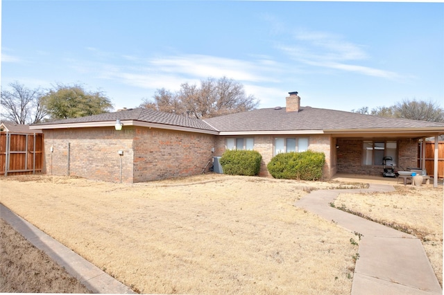 rear view of property featuring brick siding, a chimney, and fence