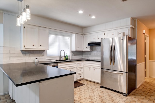 kitchen with dark countertops, a peninsula, appliances with stainless steel finishes, and a sink