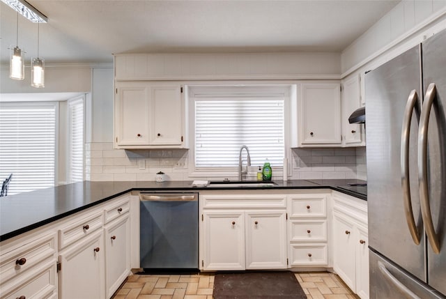 kitchen featuring stainless steel appliances, dark countertops, decorative backsplash, a sink, and under cabinet range hood