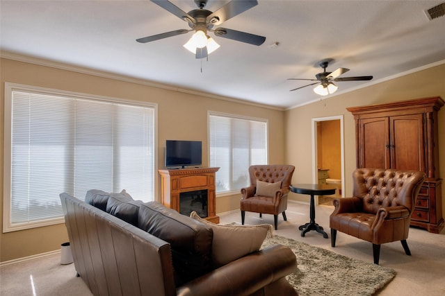 living room with visible vents, ornamental molding, a glass covered fireplace, and light colored carpet