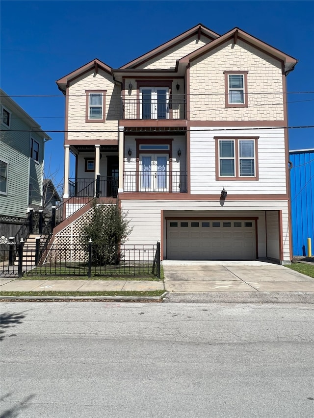 view of front of house with driveway, a garage, a balcony, a fenced front yard, and stairs