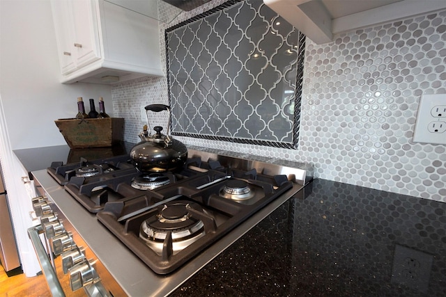 room details featuring white cabinetry, stainless steel gas cooktop, and backsplash