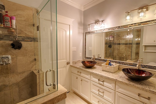 full bathroom with a stall shower, ornamental molding, and a sink