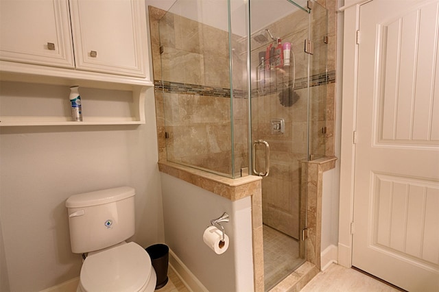 bathroom with a stall shower, toilet, and baseboards