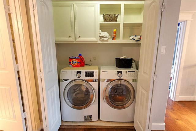 clothes washing area with wood finished floors, cabinet space, and washer and dryer