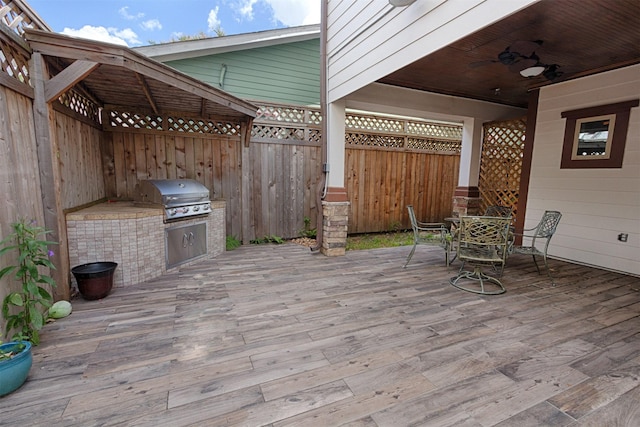 deck with outdoor dining space, fence, area for grilling, and ceiling fan