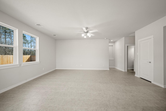 empty room featuring a ceiling fan, visible vents, and baseboards