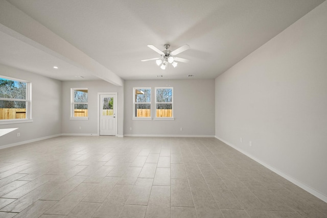 empty room featuring ceiling fan, plenty of natural light, visible vents, and baseboards