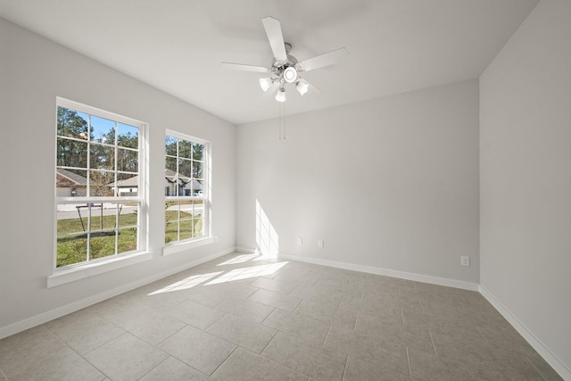 spare room with a ceiling fan, baseboards, and light tile patterned floors