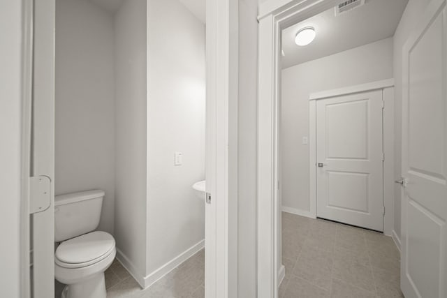 bathroom with toilet, visible vents, and baseboards