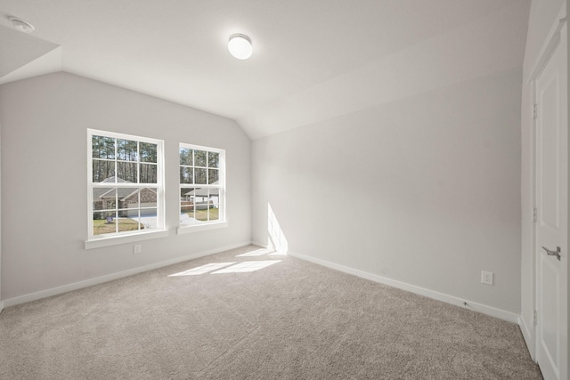 carpeted empty room with vaulted ceiling and baseboards