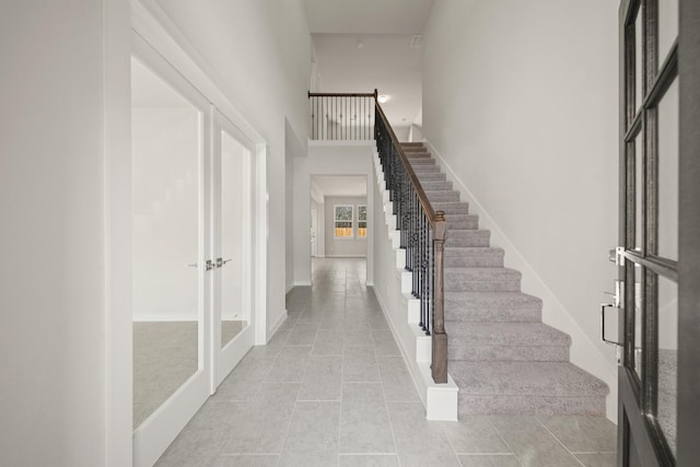 entrance foyer featuring stairs, french doors, light tile patterned flooring, and a high ceiling