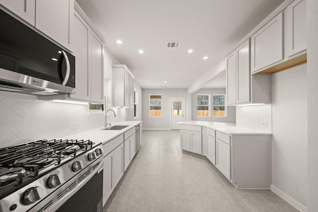 kitchen with appliances with stainless steel finishes, light countertops, a sink, and visible vents