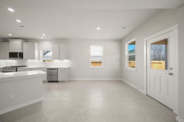 kitchen with recessed lighting, stainless steel appliances, baseboards, light countertops, and backsplash