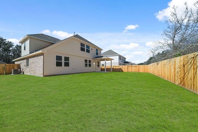 rear view of property with central AC unit, a lawn, and a fenced backyard