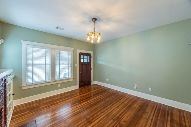 foyer entrance with a chandelier, hardwood / wood-style flooring, visible vents, and baseboards