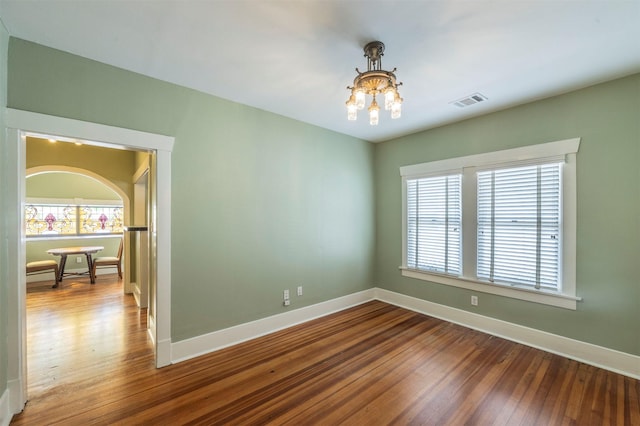 empty room with a healthy amount of sunlight, baseboards, and wood finished floors