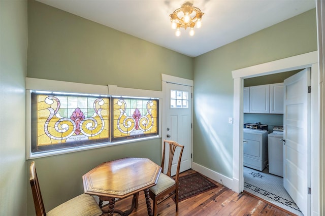 dining room with a notable chandelier, baseboards, wood finished floors, and washing machine and clothes dryer