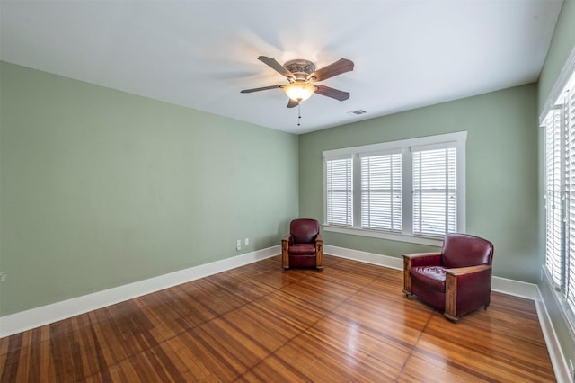 unfurnished room with a ceiling fan, wood finished floors, visible vents, and baseboards