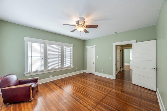 living area featuring ceiling fan, baseboards, and wood finished floors