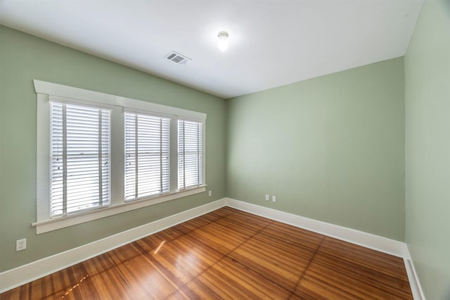 spare room featuring visible vents, baseboards, and wood finished floors