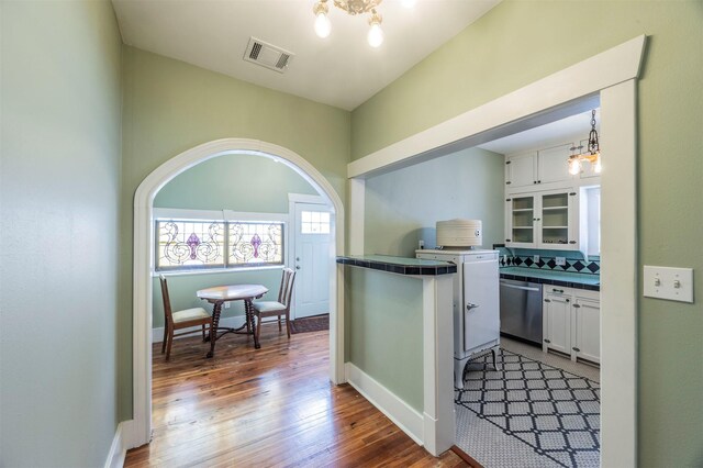 interior space featuring baseboards, wood finished floors, visible vents, and a notable chandelier