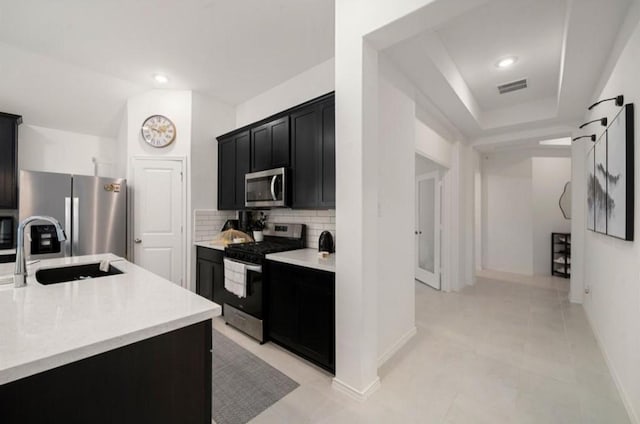 kitchen featuring visible vents, appliances with stainless steel finishes, dark cabinets, light countertops, and a sink