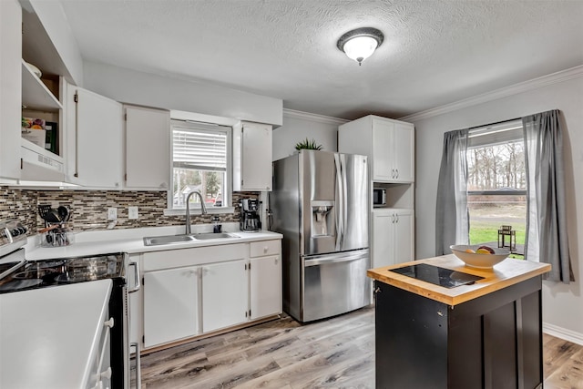 kitchen with stainless steel fridge, range with electric stovetop, a sink, and white cabinetry