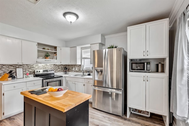 kitchen with stainless steel appliances, white cabinets, butcher block countertops, and under cabinet range hood