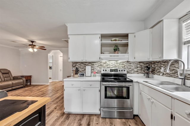 kitchen featuring range hood, electric stove, open shelves, light countertops, and a sink