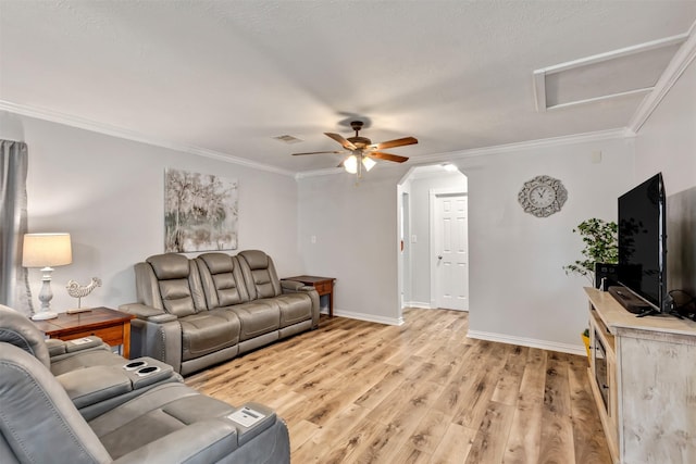 living area with attic access, baseboards, visible vents, light wood-style flooring, and crown molding