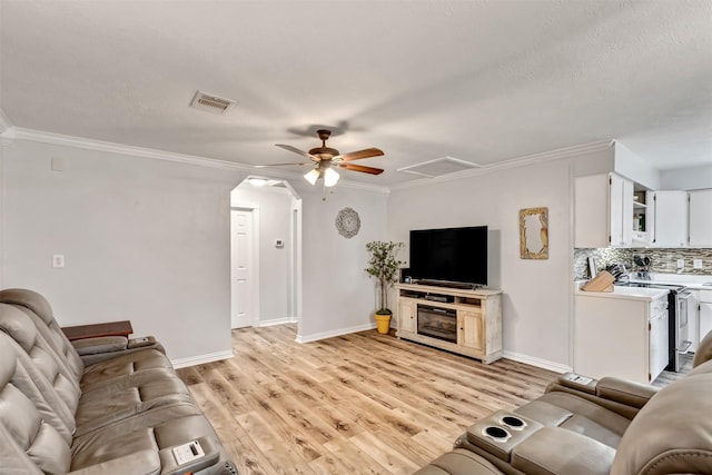 living area with light wood-style floors, baseboards, visible vents, and ornamental molding