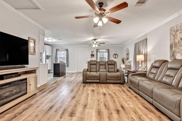 living room featuring ornamental molding, visible vents, light wood-style floors, and baseboards