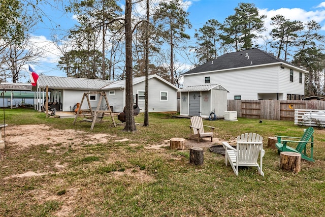 back of house with an outbuilding, a yard, a storage shed, fence, and a fire pit