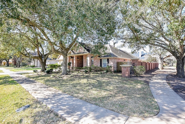 view of front of home with brick siding, a front yard, and fence