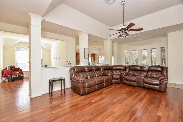 living area with ornate columns, wood-type flooring, and a ceiling fan