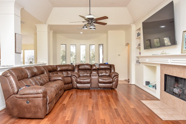 living area with built in features, light wood-type flooring, high vaulted ceiling, and a tile fireplace