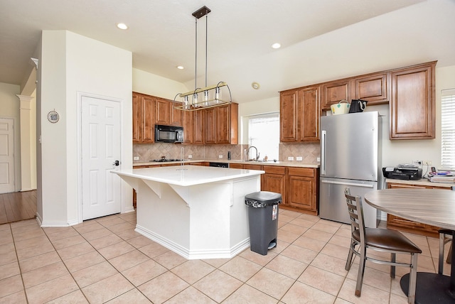 kitchen with black microwave, brown cabinets, a sink, and freestanding refrigerator