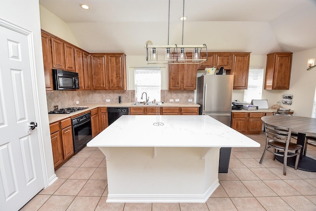 kitchen featuring light tile patterned floors, lofted ceiling, brown cabinets, black appliances, and a sink