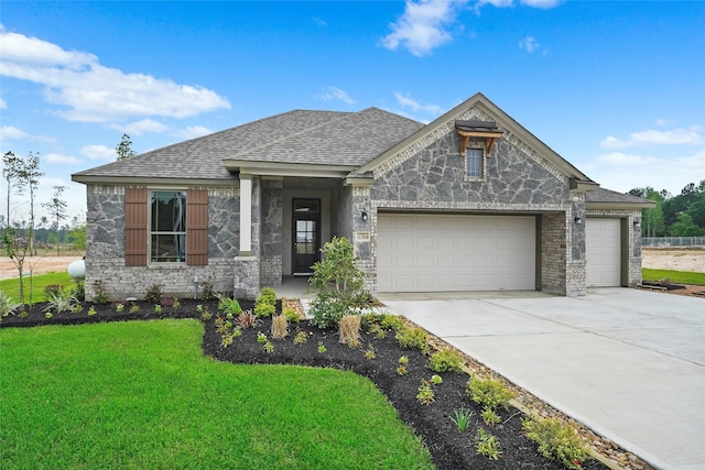 view of front facade featuring a front yard, roof with shingles, a garage, stone siding, and driveway