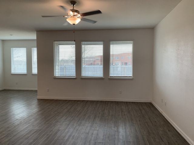 spare room featuring dark wood-style floors, baseboards, and a ceiling fan