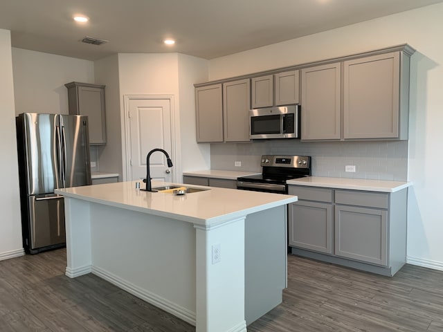 kitchen featuring stainless steel appliances, dark wood-type flooring, a sink, gray cabinets, and tasteful backsplash