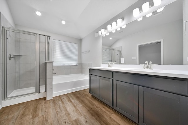 full bathroom featuring double vanity, a stall shower, a sink, wood finished floors, and a bath