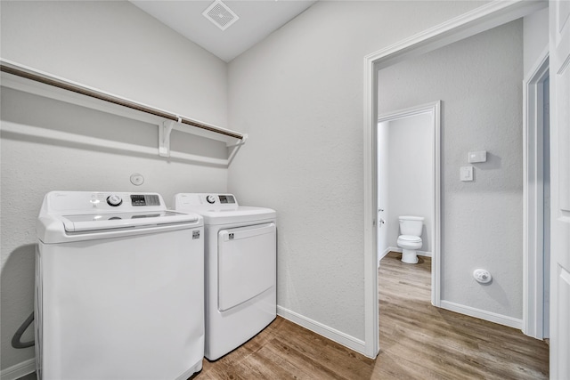 laundry area featuring laundry area, visible vents, baseboards, light wood-style floors, and independent washer and dryer