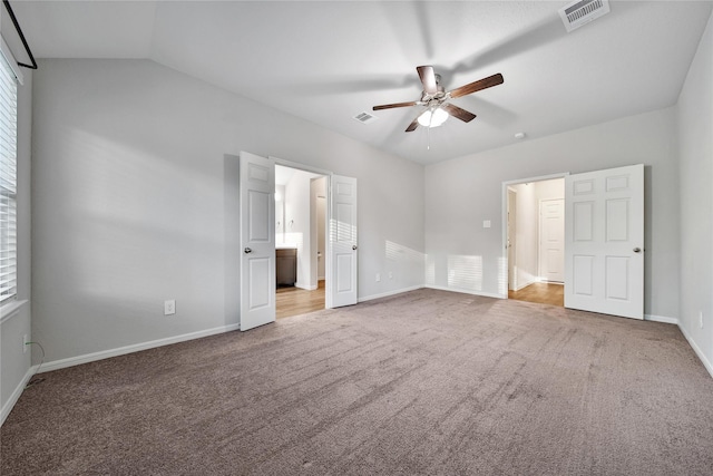 unfurnished bedroom with vaulted ceiling, carpet, visible vents, and baseboards