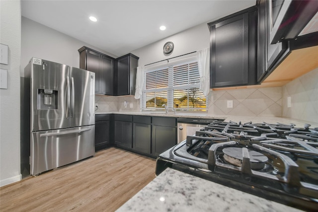 kitchen with black range with gas cooktop, dishwashing machine, a sink, light wood finished floors, and stainless steel fridge