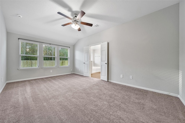 empty room with carpet floors, lofted ceiling, visible vents, ceiling fan, and baseboards