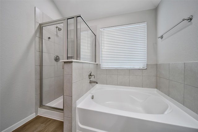 bathroom featuring a stall shower, baseboards, a garden tub, and wood finished floors