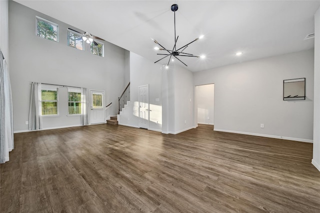 unfurnished living room featuring a notable chandelier, stairs, baseboards, and dark wood-type flooring