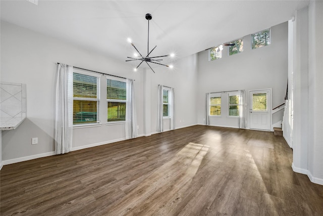 unfurnished living room featuring stairs, dark wood-style flooring, baseboards, and an inviting chandelier